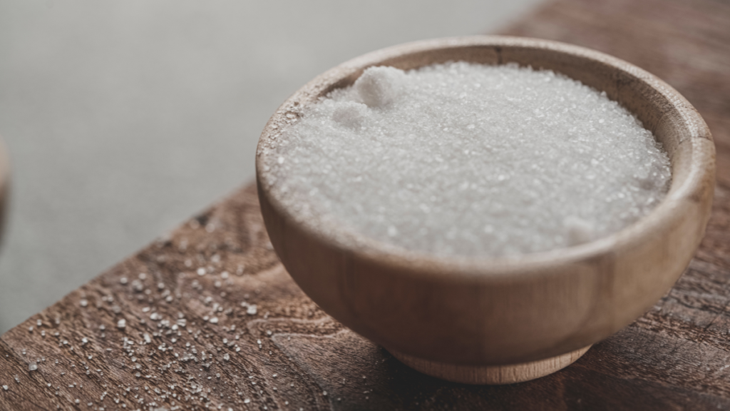 White sugar in a bowl on a wooden table