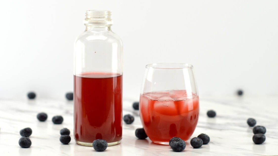 glass and bottle of blueberry kombucha
