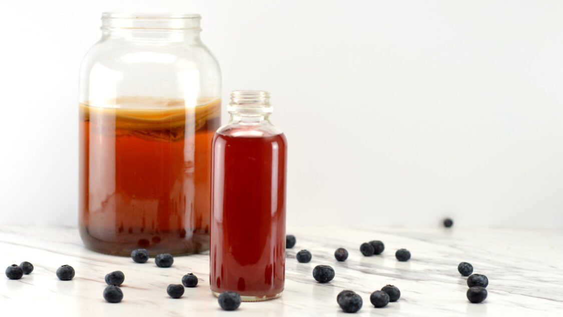 kombucha fermenter and bottle of kombucha with blueberries