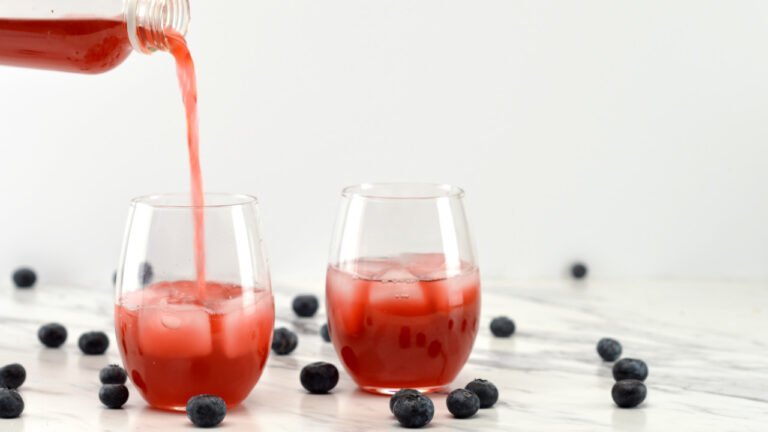 pouring blueberry kombucha into a glass