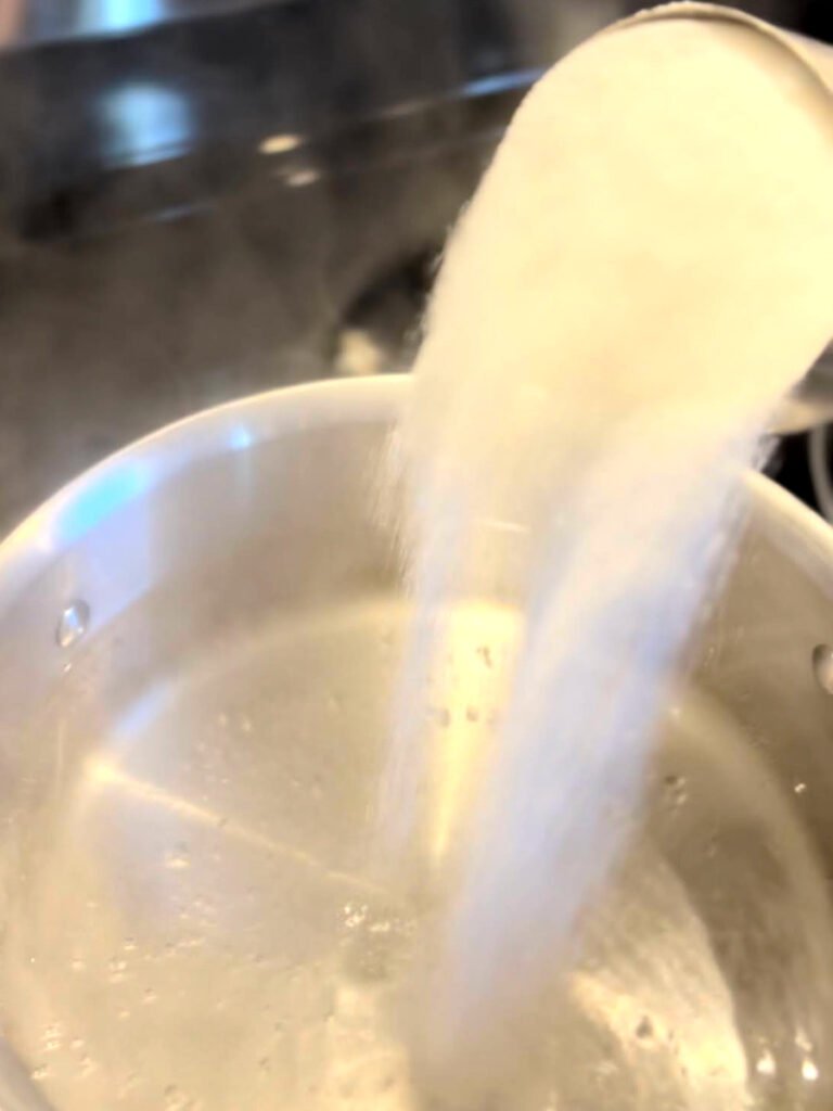 pouring sugar into pot of water