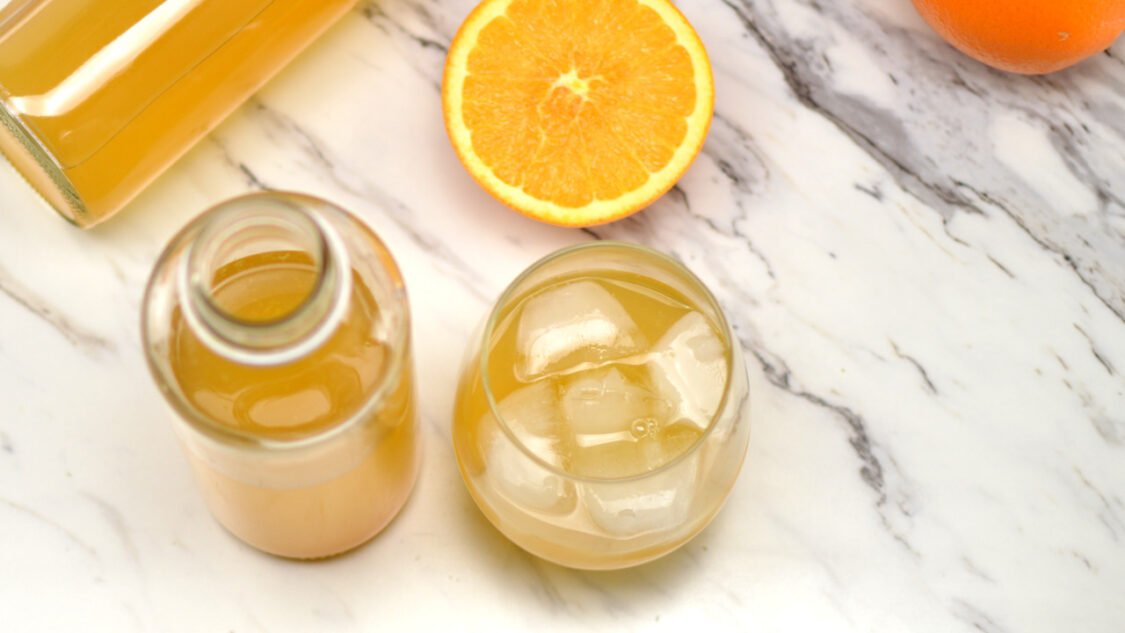 bottles of orange kombucha and glass- top